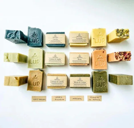 Diverse natuurlijke, ambachtelijk gemaakte zeepblokken in verschillende kleuren met ingrediënten op het etiket, plat neergelegd.