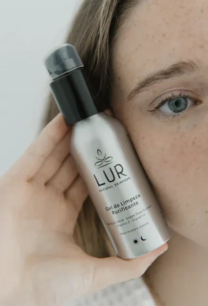 Vrouw houdt een flesje LUR natuurlijke huidverzorgingsgel dicht bij haar gezicht.