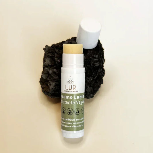 Veganistische lippenbalsem met groen etiket op natuursteen, productfotografie voor huidverzorging.