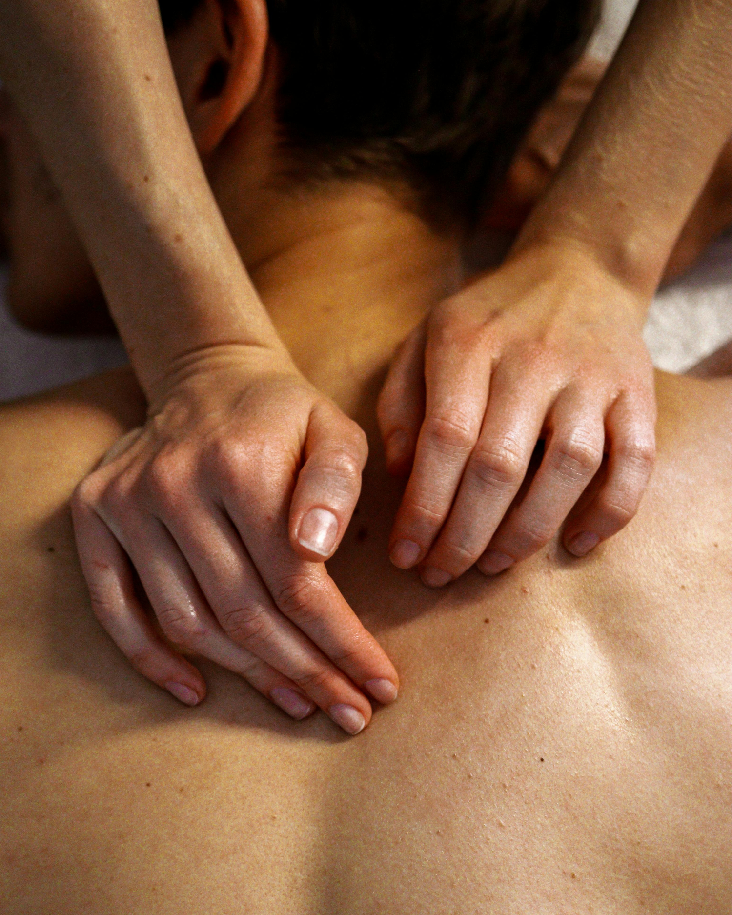 Therapist giving a back massage, hands applying pressure on bare shoulders