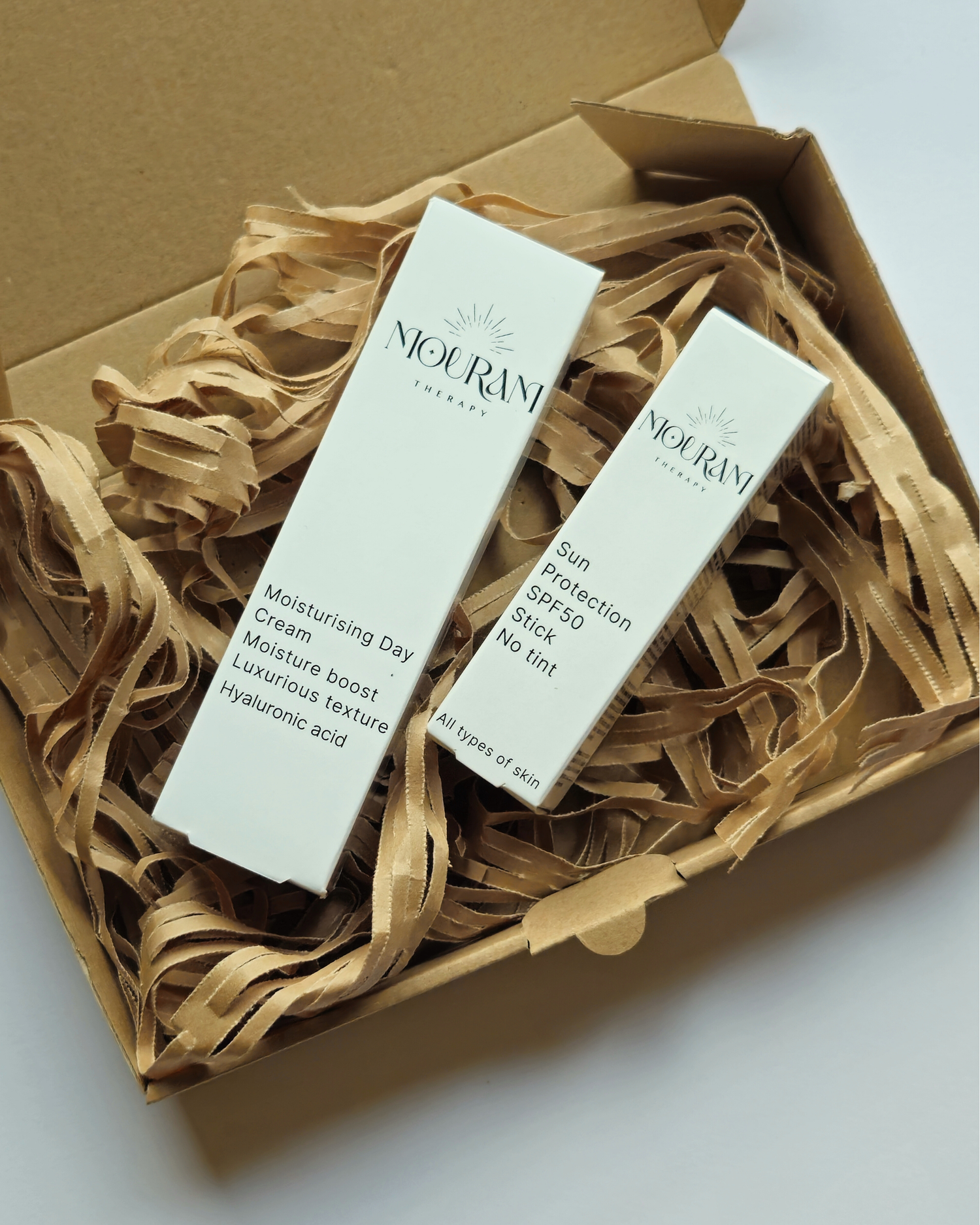 Box with Nouram Therapy moisturising day cream and sun protection SPF50 stick on shredded paper.